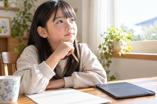 タブレットを伏せて置き、答えを見ずに思い出そうとしている小学生