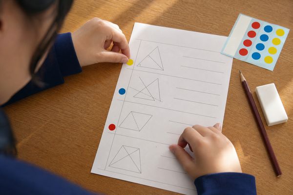 赤・青・黄の丸シールを使って、答案の間違いを3種類に分けている生徒の手元