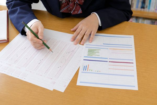 返却された答案と模試の個人成績表を並べ、鉛筆で1か所ずつ確かめている高校生の手元