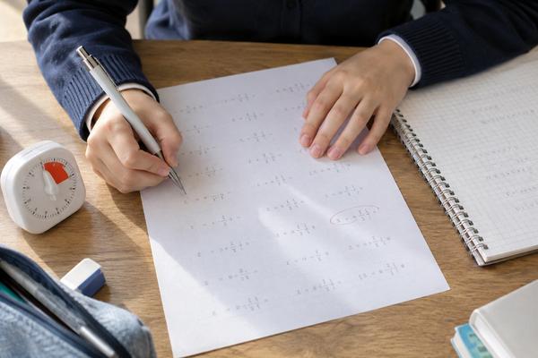 タイマーを横に置いて数学のプリントに取り組む中学生の手元