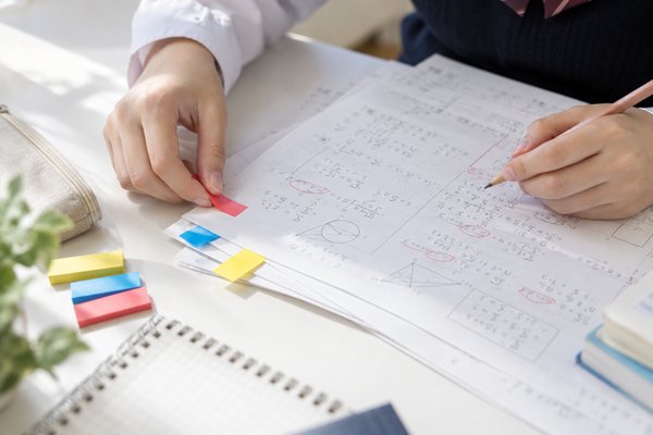 返ってきた答案とノートに色分けした付箋を貼り、間違いの種類ごとに仕分けしている手元