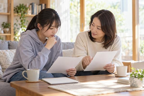 自己採点の記録と開示された得点の2枚を横に並べ、受験生と保護者が差を確かめている場面