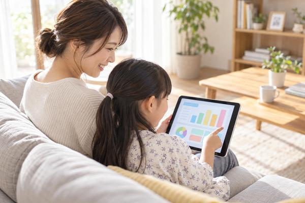 ソファで子どもと一緒にタブレットの学習履歴を見て話す母親