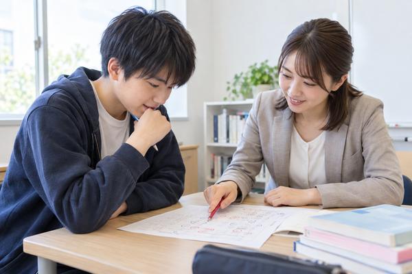 答案の誤答を指さしながら講師と一緒に失点の理由を振り返る高校生