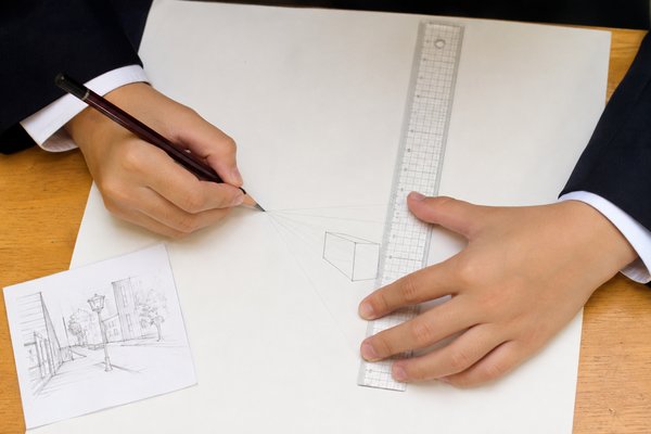 定規と鉛筆で消失点に集まる補助線を引き、透視図を小さく作図する手元