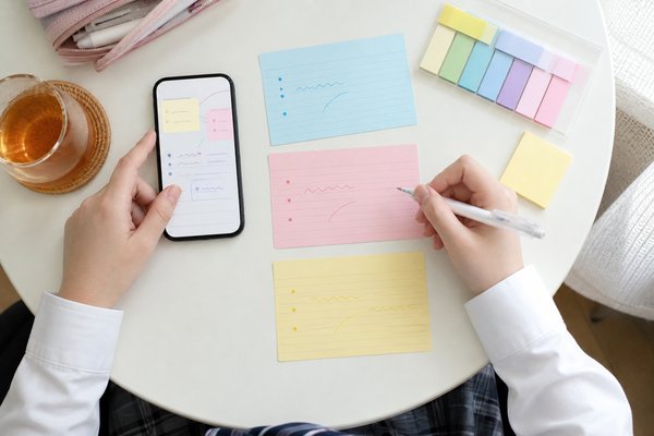 スマホのメモとカードを使って高校の候補を3校書き出している中学生の手元