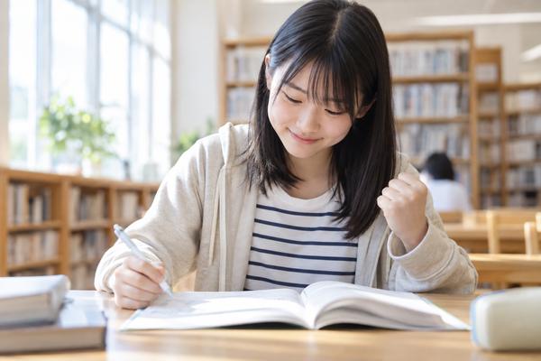図書室で中学生の女子が問題集を何も見ずに解けて、小さくガッツポーズをしながら微笑んでいる様子