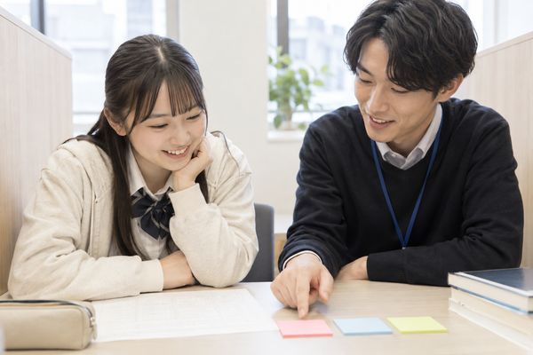 高校生と先生が答案を見ながら、知識・見分け・再現を表す3色の付箋で間違いを分ける話をしている様子