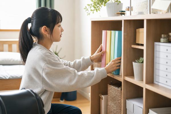 自宅で教科ごとに色分けしたファイルを棚へ整理する中学生