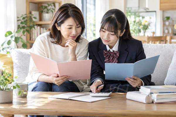 リビングで内申点の資料と模試の資料を見比べながら受験作戦を立てている母親と中学生