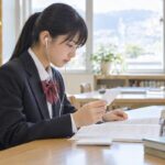 イヤホンで英語を聞きながら、問題冊子とメモを見比べる制服の中学生