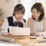 返却されたテストの答案を電卓で計算しながら母親と一緒に見直す中学生
