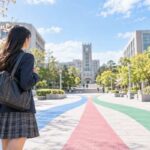 大学のキャンパスへ続く3色の道の前に立つ制服姿の高校3年生