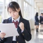 返された答案を見ながら、次に直す教科を考えている高校生