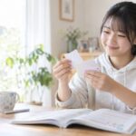 自宅のテーブルで単語カードをめくりながら、英単語の意味がすぐ出るかを確かめている中学生