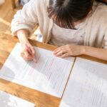 現代文の問題文と返却された答案を並べ、正解の根拠に印を付けながら見直す高校生