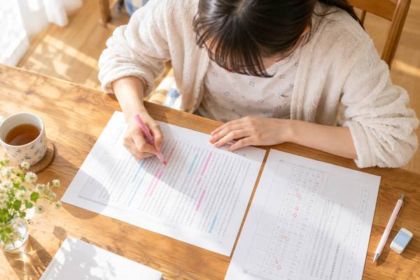 現代文の問題文と返却された答案を並べ、正解の根拠に印を付けながら見直す高校生