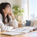 明るいリビングでTOEICの問題集とヘッドホンを前に、これからの勉強を考えている高校生