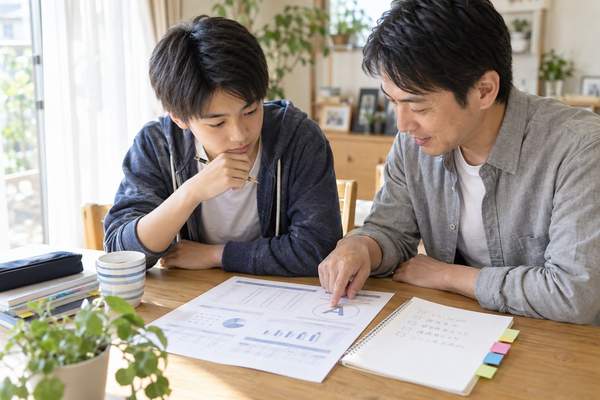 模試の成績表を見ながら次にやることを書き出す中学3年生と保護者