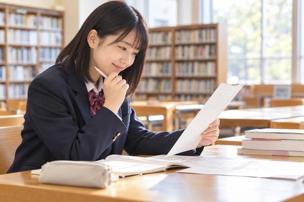 明るい学校図書室で、マーク式の漢文問題と解説を見比べて納得した表情の高校生