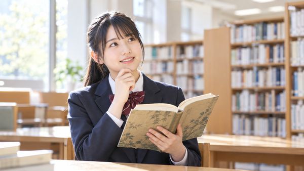 図書室で漢文の参考書を開き、ひらがなに直す漢字を確認する高校生