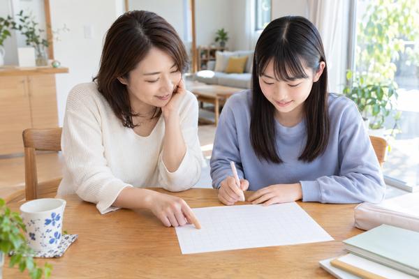 自宅のダイニングで、母親と中学生の娘が空欄の成績表テンプレートを一緒に見ている様子