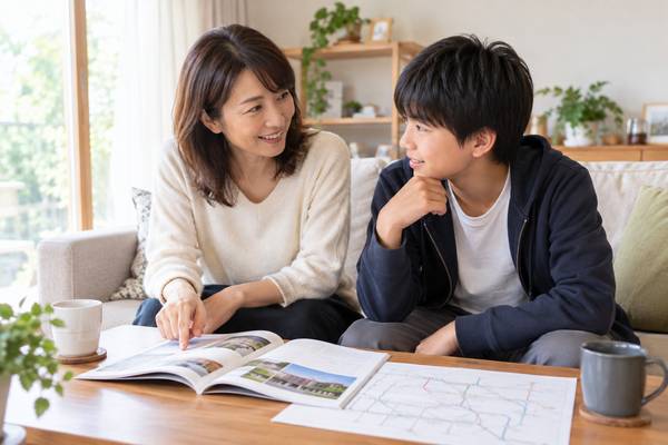 リビングで学校案内と路線図を見ながら進路を話し合う親子