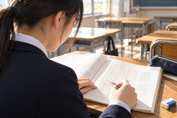 教室の机で漢文の本文に返り点を書き込み、読む順番を確かめている制服の高校生
