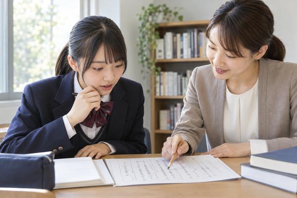 教室で、教師が漢文の一文を指しながら、否定語がどの語のまとまりにかかるかを高校生に説明している様子
