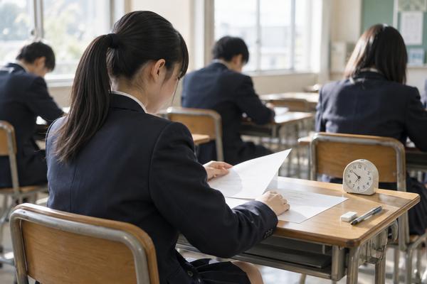 明るい試験教室で、制服の中学生が英語の問題冊子を開いている様子