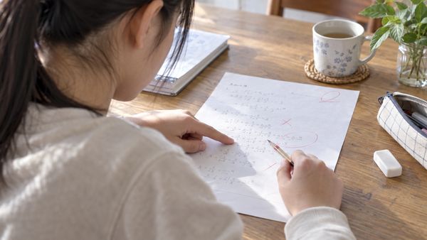 返却された数学の答案の途中式を、中学生が指でたどりながら最初に間違えた一行を探している様子
