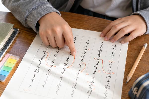 返り点の付いた漢文の練習用紙を、指で読む順番を追いながら確かめている手元