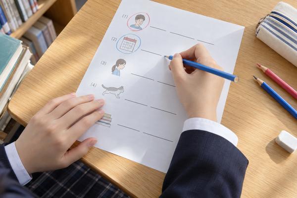 プリントの主語と時を表す部分に赤と青で印を付けながら、穴埋め問題を解く中学生の手元