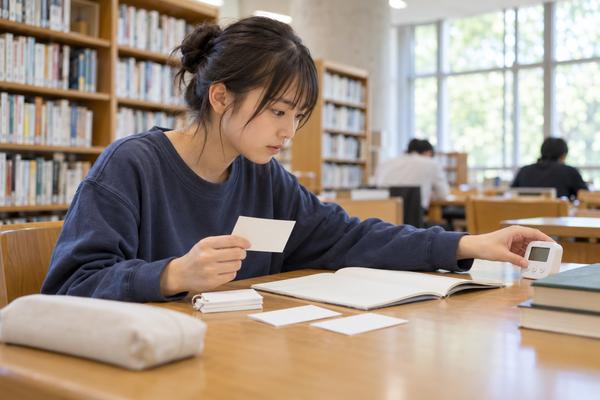 図書館で句法カードと問題集を見比べ、タイマーを押して演習に入る高校生