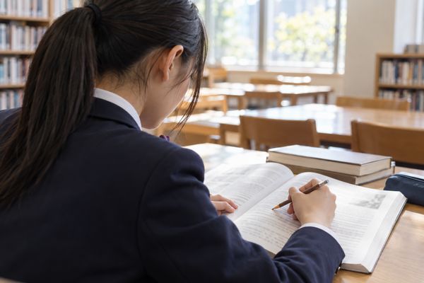 図書室で英語の長文を一文ずつ鉛筆でたどり、主語と動詞を確かめている制服の高校生