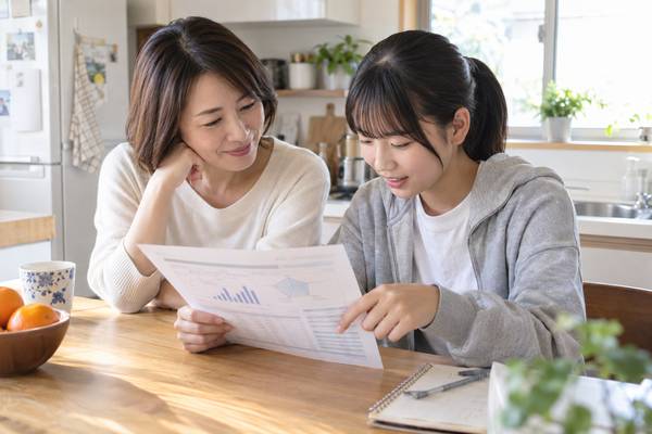 キッチンで母親と中学3年生の娘が模試の成績表を見ながら落ち着いて話し合う様子