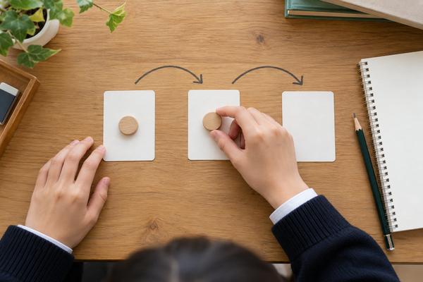 3枚のカードの上で駒を順に動かし、読む順序を確かめる高校生の手元