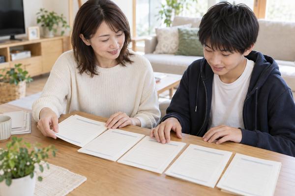 自宅のテーブルで、保護者と中学生が過去数年分の健康診断の記録を横に並べて一緒に見返している様子