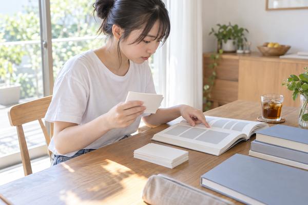 単語カードと英語の文章を交互に確認する高校3年生