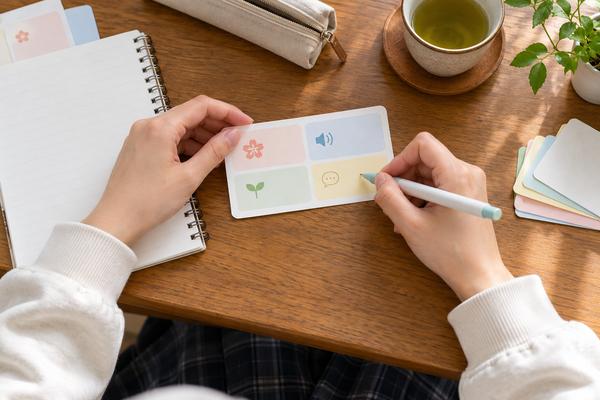 四つに区切ったカードへ漢字・読み・意味・例文を書き込んでいる高校生の手元