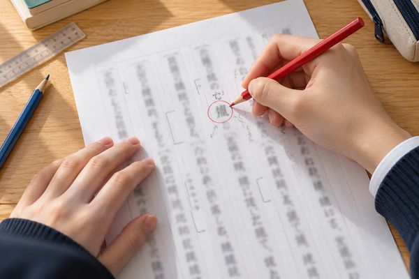 赤鉛筆で否定語を丸く囲み、かかる範囲を矢印で示しながら書き下していく手元