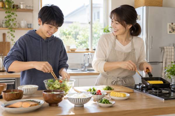 自宅のキッチンで、保護者と中学生が主食・主菜・副菜のそろった食事を一緒に用意している様子