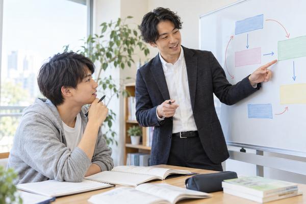 個別指導スペースのホワイトボードの前で、どの失点から回収するかを講師と相談する受験生