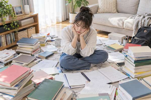 床いっぱいに広げた英語の参考書を前に手が止まっている高校3年生