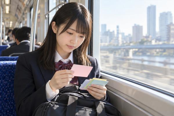 朝の通学電車の窓際で、制服の高校生がカードを使って静かに復習している様子