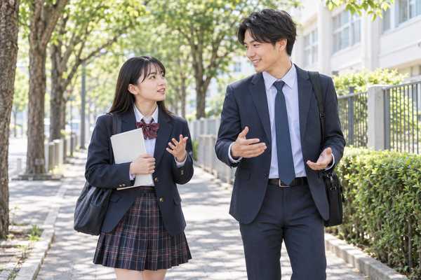 通学路を歩きながら、漢文の勉強の進め方を指導者に質問する制服の高校生