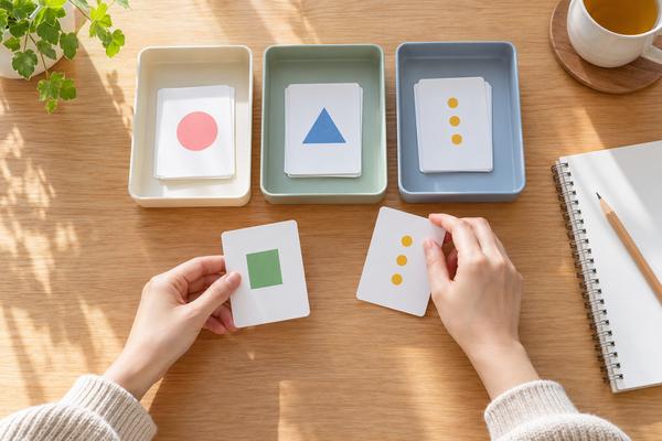 4色のカードを3つのトレーへ手順どおりに仕分けている手元